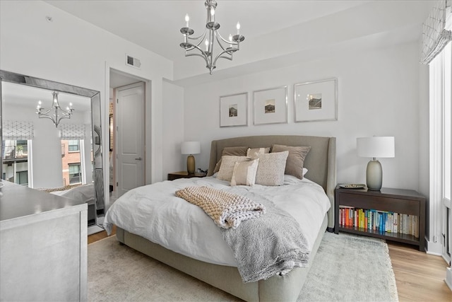 bedroom with an inviting chandelier and light wood-type flooring