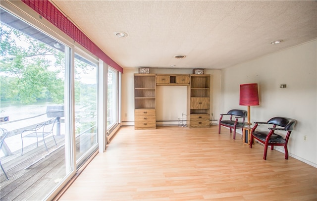 living area with wood-type flooring, a textured ceiling, and baseboard heating