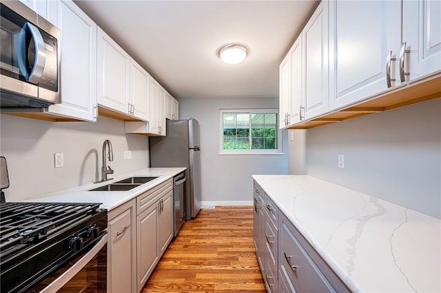 kitchen featuring stainless steel appliances, white cabinetry, light hardwood / wood-style floors, and sink