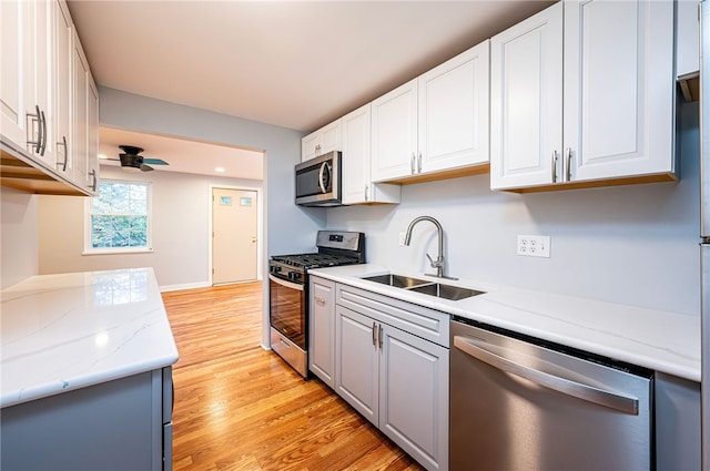 kitchen with ceiling fan, sink, light hardwood / wood-style flooring, white cabinetry, and stainless steel appliances