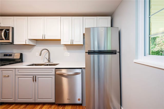 kitchen with white cabinets, sink, appliances with stainless steel finishes, and light hardwood / wood-style floors