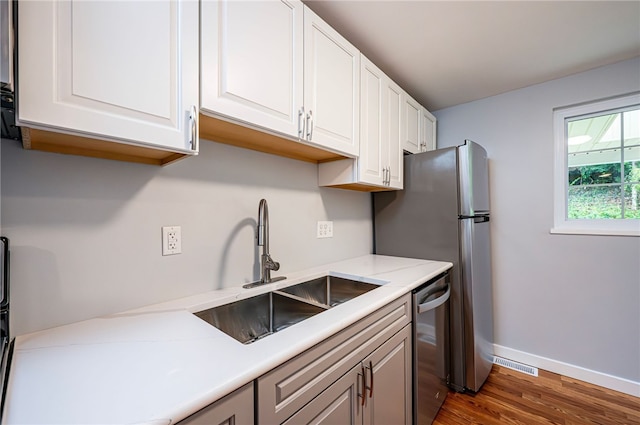 kitchen featuring dishwasher, white cabinetry, dark wood-type flooring, and sink