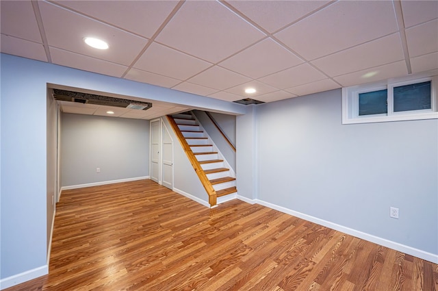 basement with wood-type flooring and a paneled ceiling