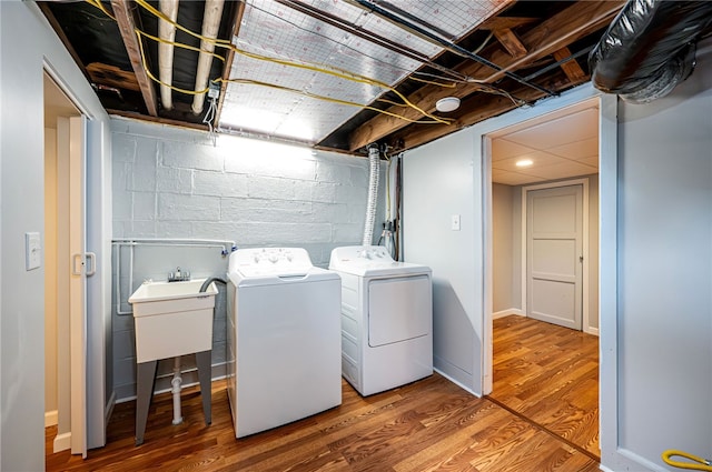 washroom with separate washer and dryer, sink, and hardwood / wood-style floors