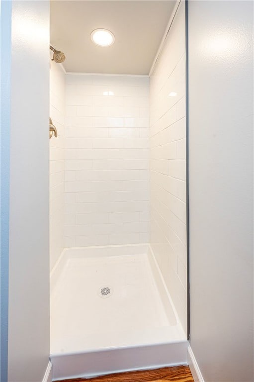 bathroom with hardwood / wood-style flooring and tiled shower