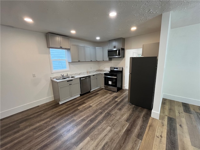 kitchen with a textured ceiling, sink, gray cabinetry, stainless steel appliances, and dark hardwood / wood-style flooring