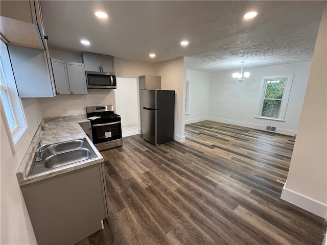 kitchen featuring sink, gray cabinetry, a chandelier, stainless steel appliances, and dark hardwood / wood-style flooring