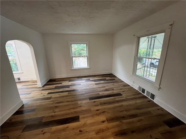 empty room with a textured ceiling and dark hardwood / wood-style floors