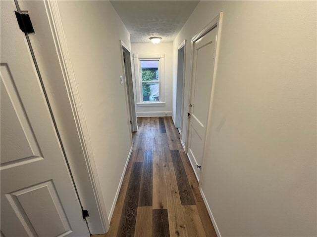 hall featuring a textured ceiling and dark hardwood / wood-style floors