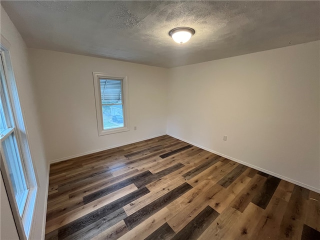 spare room with a textured ceiling and dark hardwood / wood-style flooring