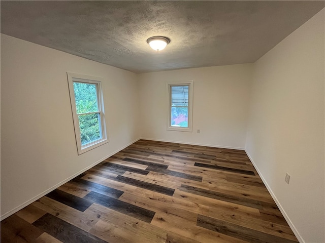 spare room featuring a textured ceiling and dark hardwood / wood-style floors