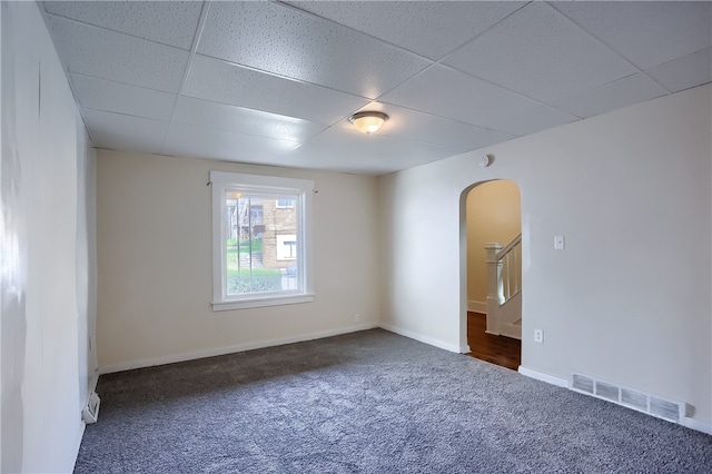 spare room with a paneled ceiling and dark carpet