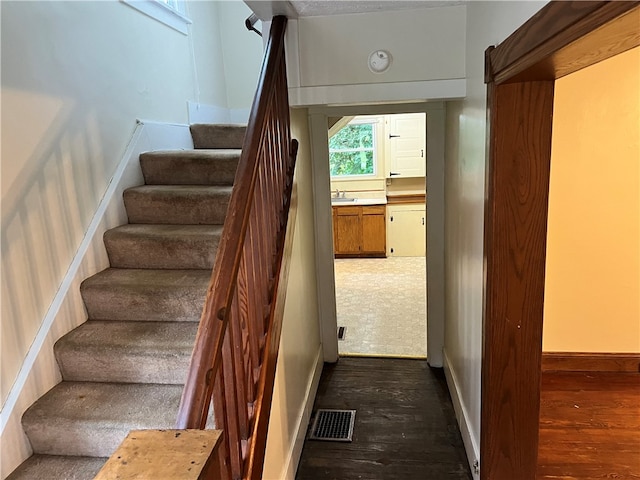 stairway with hardwood / wood-style floors and sink