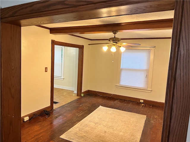 unfurnished room featuring ornamental molding, beam ceiling, ceiling fan, and dark hardwood / wood-style floors