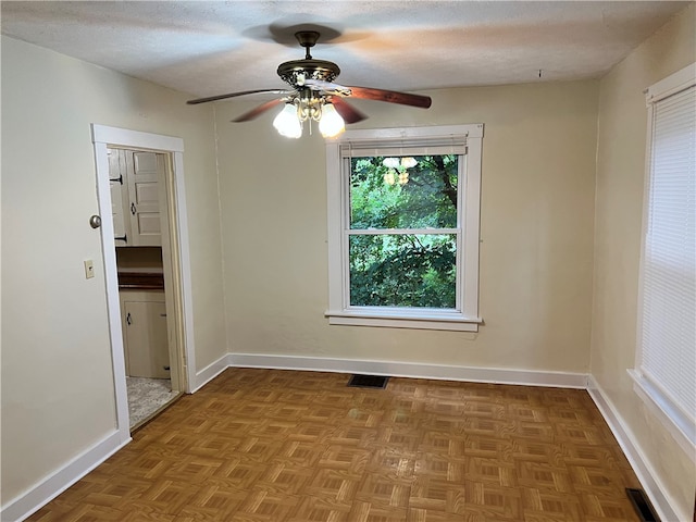 unfurnished room with ceiling fan, a textured ceiling, and parquet floors