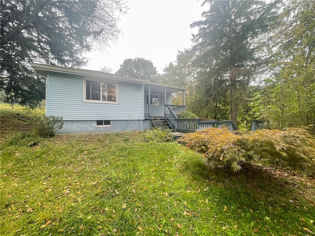 rear view of house with a lawn and a wooden deck