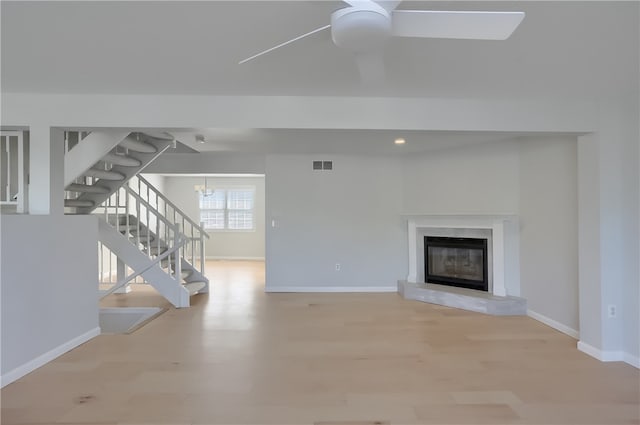 unfurnished living room featuring light wood-type flooring, ceiling fan, and a fireplace