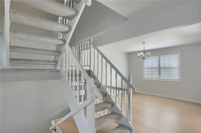 stairway featuring hardwood / wood-style floors and an inviting chandelier