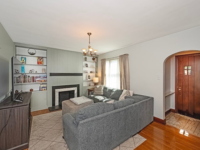 living room featuring light hardwood / wood-style flooring, a large fireplace, and a notable chandelier