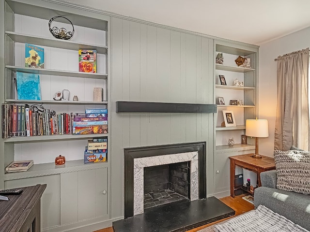 living area featuring wood-type flooring, wooden walls, and a premium fireplace