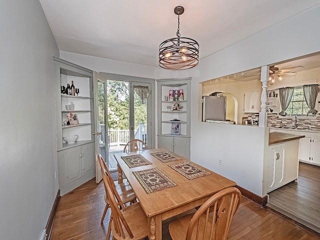 dining space featuring a healthy amount of sunlight, ceiling fan with notable chandelier, and dark hardwood / wood-style floors