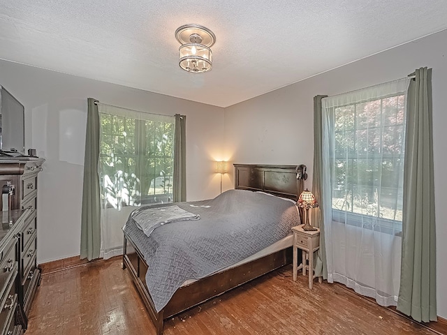 bedroom featuring multiple windows, a textured ceiling, and hardwood / wood-style floors