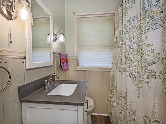 bathroom with vanity, a shower with shower curtain, hardwood / wood-style flooring, wooden walls, and toilet