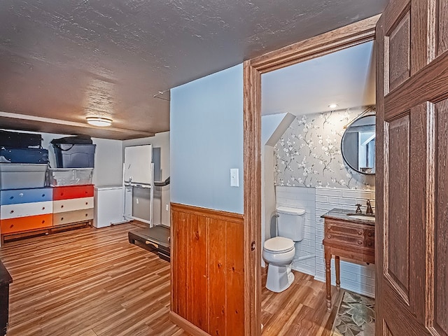 bathroom with wood-type flooring, vaulted ceiling, vanity, and toilet