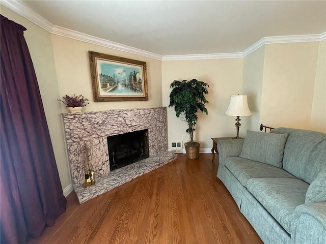 living area featuring ornamental molding, baseboards, wood finished floors, and a fireplace