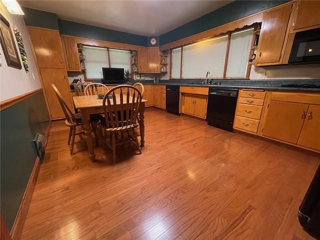 kitchen featuring black appliances, dark countertops, light wood-style floors, a sink, and open shelves