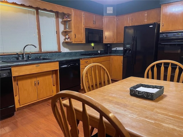 kitchen featuring black appliances, a sink, light wood-style flooring, open shelves, and brown cabinetry