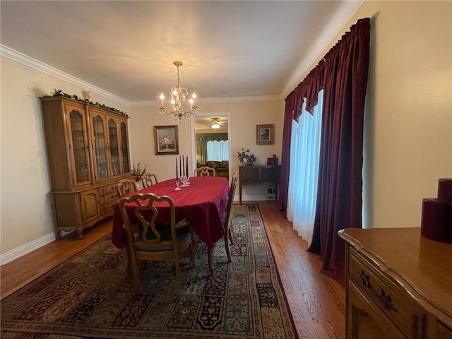 dining area with ornamental molding, a chandelier, and dark hardwood / wood-style flooring