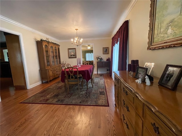 dining area with ornamental molding, an inviting chandelier, and hardwood / wood-style floors