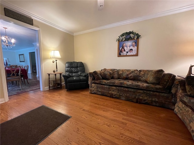 living room with ornamental molding, a chandelier, and hardwood / wood-style flooring