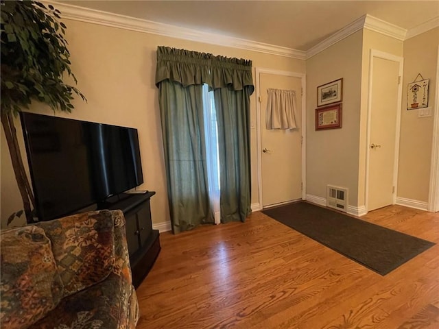 living area with wood finished floors, ornamental molding, and baseboards