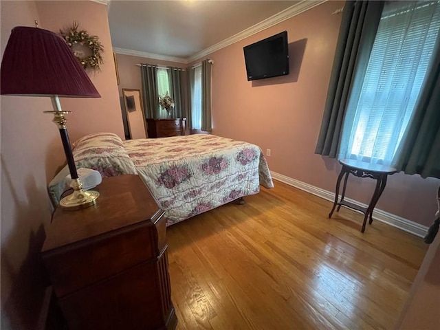 bedroom featuring baseboards, wood finished floors, and crown molding