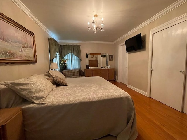 bedroom with a chandelier, wood finished floors, ornamental molding, a closet, and baseboards