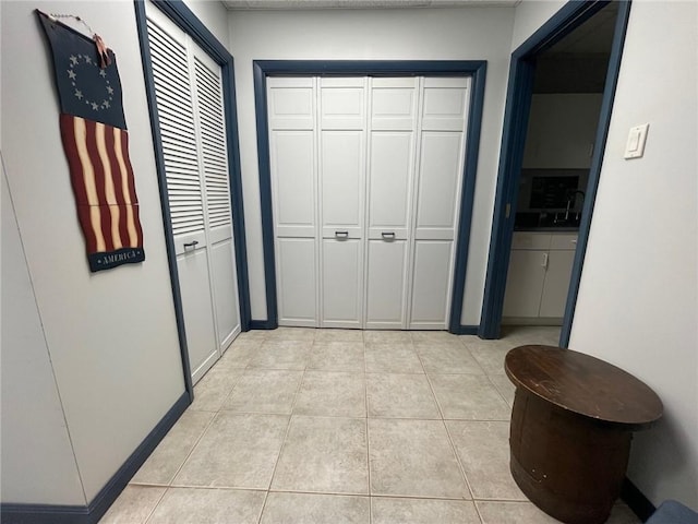 corridor featuring light tile patterned floors and baseboards