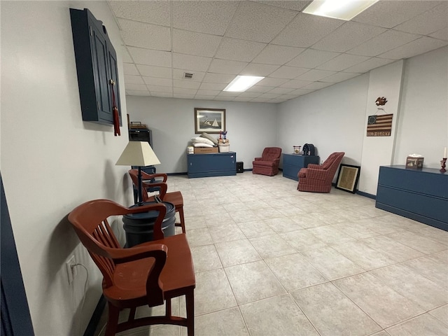 living area featuring a drop ceiling and light tile patterned flooring