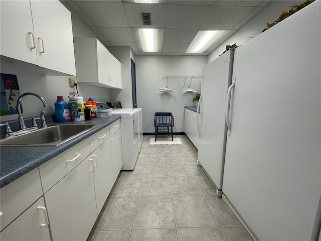 kitchen with washer and dryer, sink, white cabinets, a paneled ceiling, and light tile patterned floors