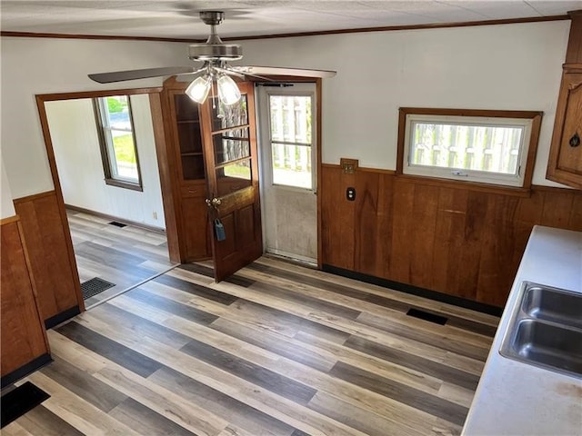 interior space featuring light hardwood / wood-style floors, wood walls, lofted ceiling, ceiling fan, and sink