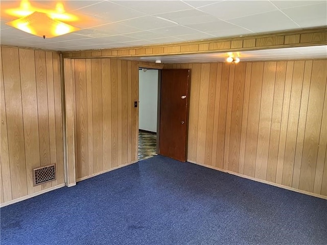 carpeted spare room with wooden walls