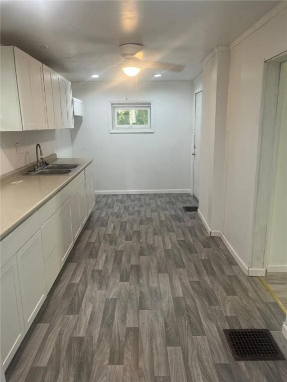 kitchen featuring dark wood-type flooring, sink, white cabinetry, and ornamental molding