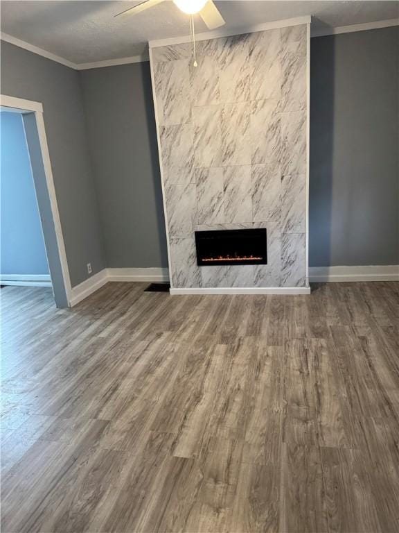 unfurnished living room with ceiling fan, a fireplace, crown molding, and hardwood / wood-style floors