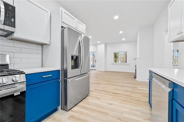 kitchen featuring blue cabinets, appliances with stainless steel finishes, light hardwood / wood-style floors, and white cabinetry