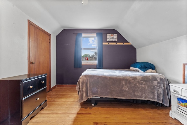 bedroom featuring light wood-type flooring and vaulted ceiling