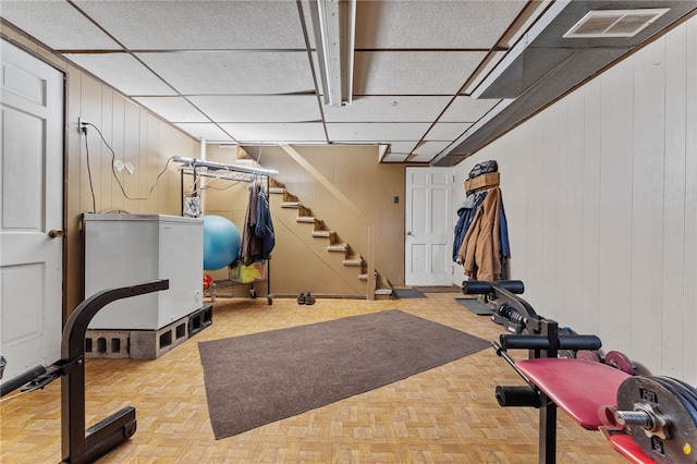 exercise room with wood walls and parquet floors