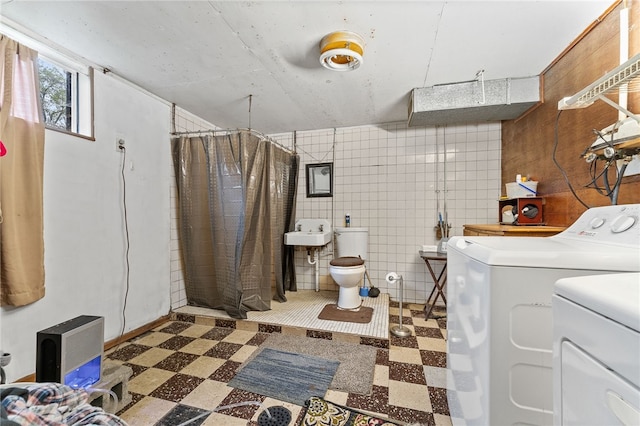 bathroom with sink, washing machine and dryer, a shower with curtain, tile walls, and toilet