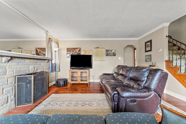 living room featuring a stone fireplace, ornamental molding, and hardwood / wood-style flooring