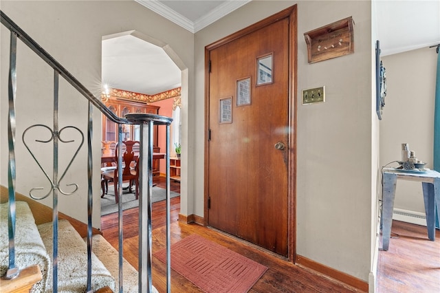 foyer entrance with wood-type flooring, baseboard heating, and crown molding